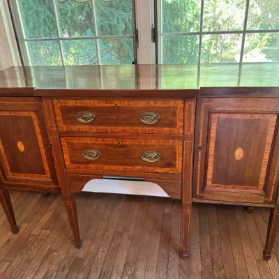 Antique Hepplewhite-style mahogany sideboard featuring satinwood inlay, oval brass hardware, and two central drawers flanked by side...