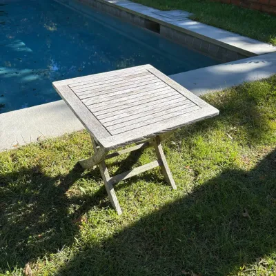 Weathered teak slatted folding side table, ideal for patio or poolside use.