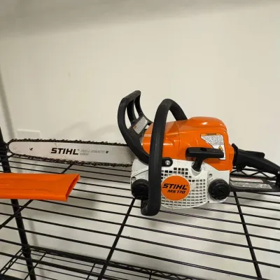 Sale Photo Thumbnail #145: Stihl MS 170 gas-powered chainsaw with Rollomatic E Mini guide bar and orange bar scabbard, showing light use.