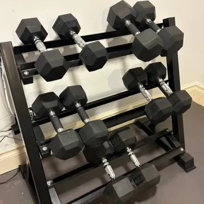 Sale Photo Thumbnail #133: Three-tier black steel dumbbell rack with various rubber-coated hex dumbbells, including 20 lb, 25 lb, 30 lb, and 40 lb pairs.