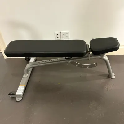 Sale Photo Thumbnail #136: Paramount adjustable weight bench with silver powder-coated steel frame and black vinyl padding.