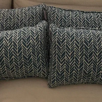 Set of four rectangular throw pillows with a black and beige chevron weave pattern and piped edges.