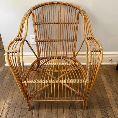 Sale Photo Thumbnail #109: Vintage wicker and rattan armchair featuring a curved backrest and slatted openwork construction.