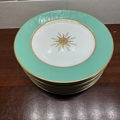 Stack of mid-century fine china porcelain plates featuring mint green rims with gold trim and a central gilt sunburst motif.