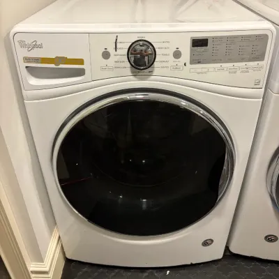 Sale Photo Thumbnail #138: Modern white Whirlpool front-loading washing machine featuring a chrome-trimmed door, digital control panel, and central selector dial.