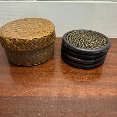 Small woven round lidded basket paired with a set of dark wood and woven seagrass coasters.