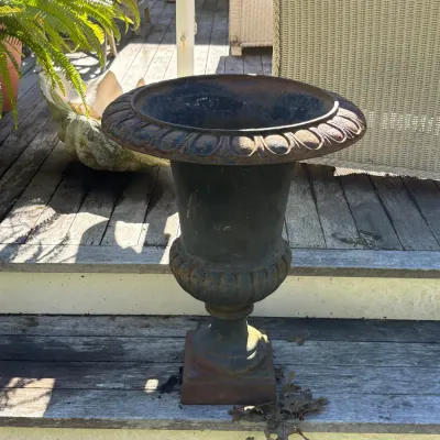 Cast iron garden urn planter with egg-and-dart rim detailing and an weathered, aged finish.