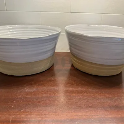 Pair of modern ceramic serving bowls featuring a white ribbed glazed top and exposed natural clay bases.