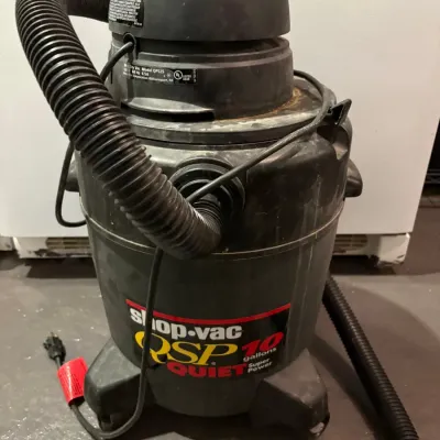 Sale Photo Thumbnail #146: Shop-Vac QSP Quiet Super Power 10-gallon wet/dry vacuum with attached hose and power cord, showing light surface dust from previous use.