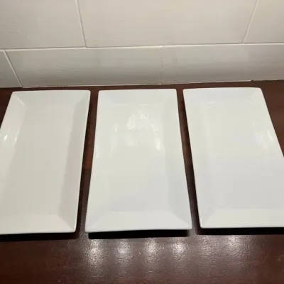 Set of three matching rectangular white ceramic serving platters in simple, modern style.