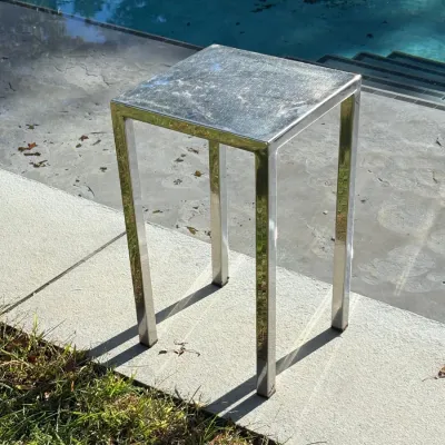Sale Photo Thumbnail #123: Modernist polished chrome square accent table with straight pedestal legs, shown outdoors near a pool.