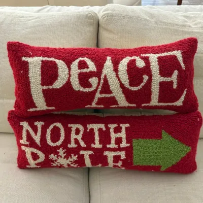 Pair of rectangular Christmas-themed hooked wool throw pillows featuring "PEACE" and "NORTH POLE" with a green arrow.