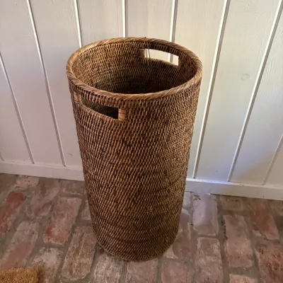 Sale Photo Thumbnail #122: Tall, cylindrical woven rattan basket with built-in side handles, ideal for laundry or umbrella storage.