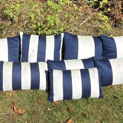 Set of seven blue and white striped outdoor throw pillows in square and rectangular shapes.