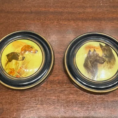 Pair of vintage round framed dog portraits featuring pointers and shepherds, set in black and brass-toned circular frames.
