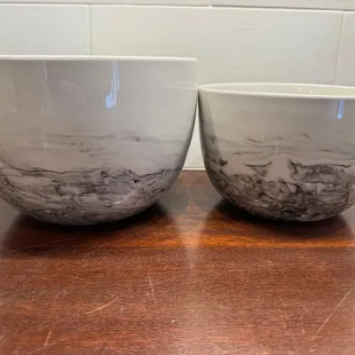 Pair of modern ceramic nesting mixing bowls with a white glazed upper section and marbled grey and black lower body design.