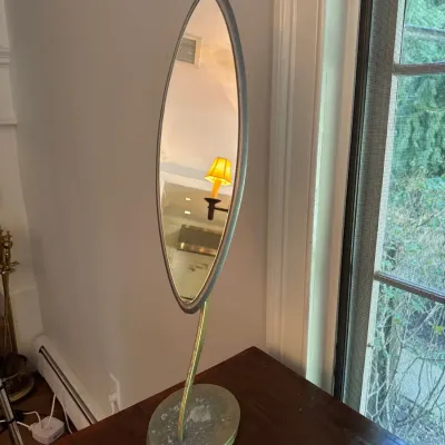 Mid-century modern oval vanity tabletop mirror on a curved brass pedestal base.
