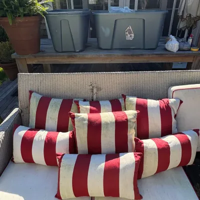 White wicker outdoor sofa set with cream seat cushions and red-and-white striped accent pillows.