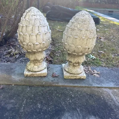 Pair of weathered concrete pinecone finials on pedestal bases with a natural distressed patina.