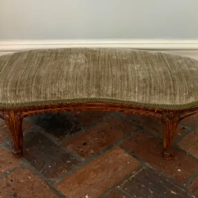 Sale Photo Thumbnail #115: French Provincial style kidney-shaped ottoman or bench featuring carved wooden legs and olive green striped velvet upholstery with decorative gimp trim.
