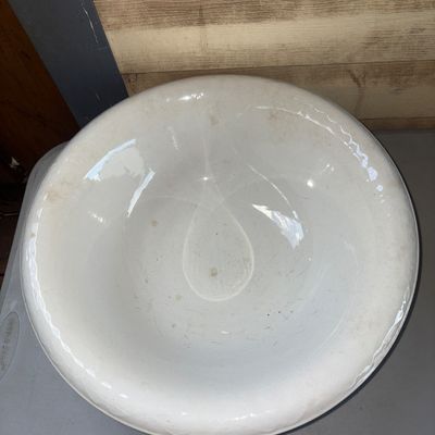 Sale Photo Thumbnail #379: A large, classic white ceramic or ironstone wash basin bowl featuring a wide rolled rim. Shows light age-related wear, minor surface discoloration, and fine crazing consistent with age and use. Ideal for rustic, farmhouse, or traditional decor.
16in