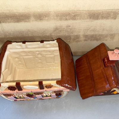 Sale Photo Thumbnail #171: Ceramic or painted earthenware cookie jar shaped like a gingerbread house with candy and cookie details. Features a removable roof lid with chimney handle. Glossy glazed finish. Appears to be in good condition with no visible cracks or chips.
14in tall