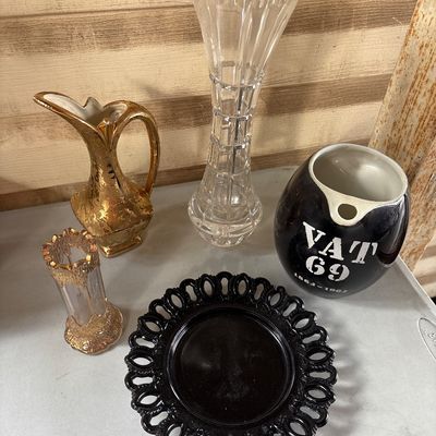 Sale Photo Thumbnail #69: Collection of five vintage glass, ceramic, and barware items including a clear cut glass vase, a black ceramic 'VAT 69' scotch whisky water pitcher/jug (marked 1863-1963), a black glass open-work lace edge plate, a small gold-gilt porcelain pitcher, and a