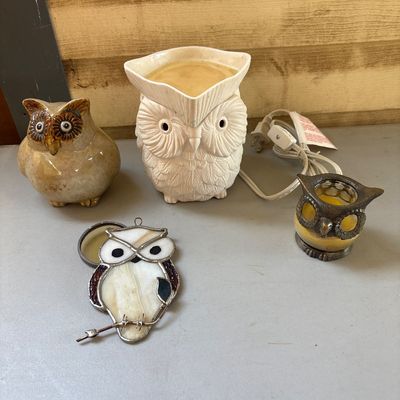 Sale Photo Thumbnail #14: A 4-piece collection of owl-themed decorative items. Includes an electric ceramic white owl wax warmer/fragrance lamp with cord, a glazed ceramic owl figurine, a metal and yellow glass owl votive candle holder, and a stained glass owl sun catcher/hanging 