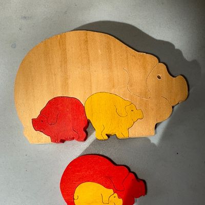 Sale Photo Thumbnail #67: Set of handcrafted wooden pig family nesting/interlocking puzzles featuring natural wood and painted red and yellow pig figures. Shows minor vintage wear consistent with age and use.