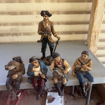 Sale Photo Thumbnail #151: Collection of five detailed resin pirate figurines, including four shelf sitters and one standing pirate captain with a sword and treasure chest base. Figures feature nautical details like eyepatches, treasure chests, and telescopes. 

Condition: Note tha
