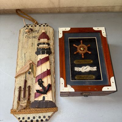 Sale Photo Thumbnail #45: Set of two nautical-themed decor pieces. Includes a wooden hanging plaque featuring a lighthouse, seagull, anchor, and 'Welcome Friends' text, alongside a wooden shadow box displaying a miniature ship's wheel and reef knot with brass labels. Both items ar