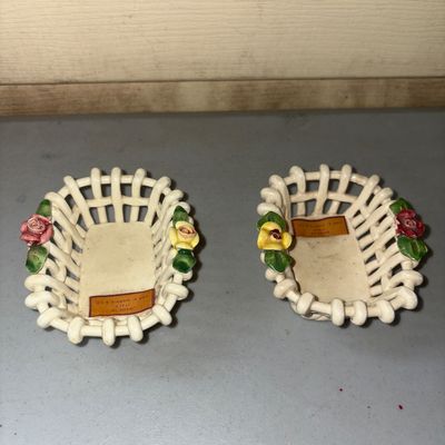 Sale Photo Thumbnail #81: A pair of small, openwork ceramic lattice/woven baskets featuring applied porcelain rose and leaf details on either end. Each basket includes an original label reading 'Made in Italy for A. Harris & Co.'. Showing light wear and dust consistent with age, b