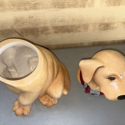 Sale Photo Thumbnail #257: Glazed ceramic cookie jar shaped like a sitting yellow Labrador Retriever wearing a red collar. Features a removable head lid. Shows light crazing in the glaze visible on the body; otherwise in good condition with no apparent chips or cracks.
12in tall