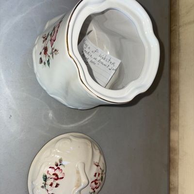 Sale Photo Thumbnail #185: Lidded ceramic or porcelain container featuring a molded swirl pattern, gilded trim, and pink floral rose motifs. Appears in good overall condition with minor wear to the gilt accent trim.
7in tall