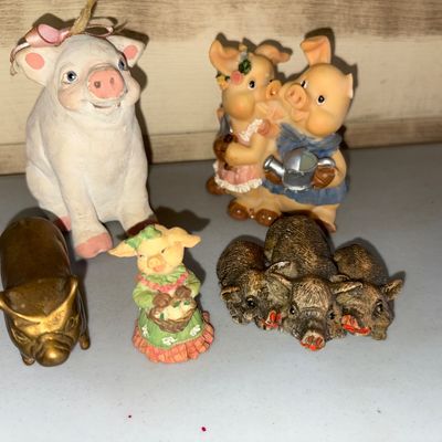Sale Photo Thumbnail #29: Collection of five pig figurines in various styles and materials. Includes a brass/bronze-tone pig, a resin pig couple with a watering can, a larger white pig ornament with a pink bow, a small pig figurine in a green dress, and a group sculpture of three 