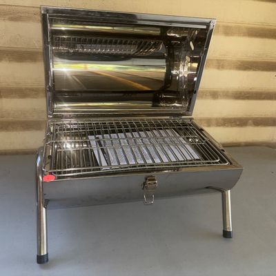 Sale Photo Thumbnail #279: Portable stainless steel tabletop barbecue grill branded with National Wild Turkey Federation (NWTF) logo. Features a wooden carry handle, folding legs, latching lid, and cooking grate inside. Appears clean and unused with paperwork included inside.
15X16