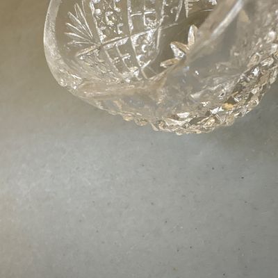 Sale Photo Thumbnail #211: Pair of clear pressed or cut glass cups featuring intricate diamond geometric patterns, textured handles, and starburst bases. Ideal for punch, tea, or decorative use. Both pieces appear to be in good condition with minor surface wear consistent with age 