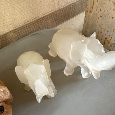 Sale Photo Thumbnail #31: Collection of small decorative animal figurines and a miniature lighthouse. Includes two carved quartz/alabaster style stone elephant figures, two textured ceramic or resin pig/warthog figures, one painted resin bunny with flowers figurine, and one tiny b