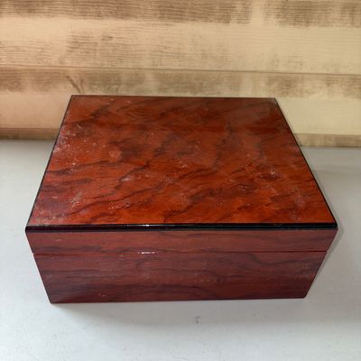 Sale Photo Thumbnail #103: Savoy desktop cigar humidor featuring a rich reddish-brown polished wood finish and Spanish cedar lining. Inside includes an attached Savoy humidifier element, loose wooden divider pieces, and various small accessories. Shows minor surface dust and light 