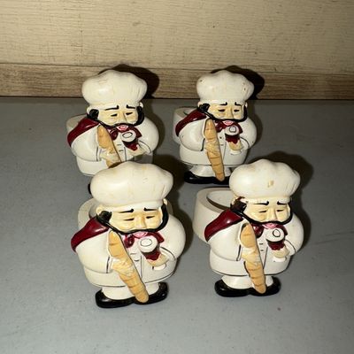 Sale Photo Thumbnail #79: Set of four painted resin or ceramic chef napkin rings. Each figure depicts a French chef holding a baguette and a glass. Showing light surface wear and minor paint scuffs consistent with age and use.