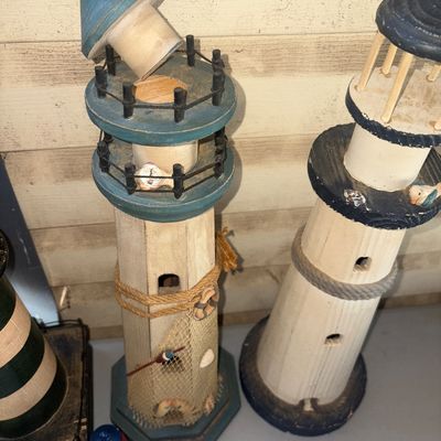 Sale Photo Thumbnail #277: Set of four decorative wooden lighthouse figurines in various sizes and nautical styles. Features painted finishes, rope accents, netting details, and crackle paint effects. Items show light surface wear consistent with age and display. The top cap on one