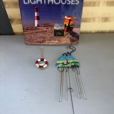 Sale Photo Thumbnail #226: A nautical/lighthouse themed collection including 'Heritage Lighthouses' hardcover book by Alex Greene, a painted lighthouse wind chime with metal tubes, and a small life preserver ring ornament. All items appear to be in good pre-owned condition with lig