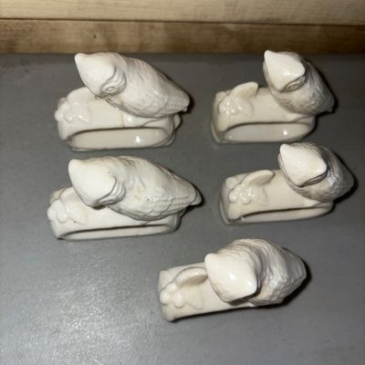 Sale Photo Thumbnail #78: A set of five white ceramic or porcelain napkin rings featuring sculpted owl figures perched on branches. Glossy finish. Overall good condition with light surface wear and minor discoloration consistent with age and use. Small visible cracks on one but in