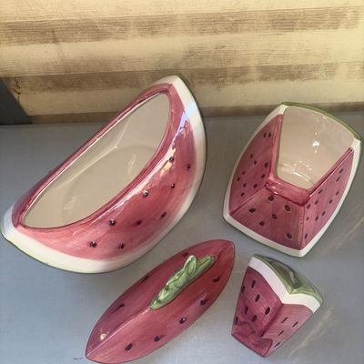 Sale Photo Thumbnail #246: Set of two glazed ceramic decorative containers shaped like watermelon slices, complete with removable lids. One features a green leaf handle on top, and the other is styled as an upright slice. Shiny glazed finish in pink, green, and white with painted s