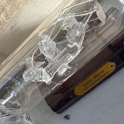 Sale Photo Thumbnail #346: Collection of three glass decorative items including a hand-blown glass ship in a bottle mounted on a wooden base labeled 'Santa Maria 1492 Columbus' Flagship' (note: glass rigging inside bottle appears broken/detached), alongside two laser-etched crystal
