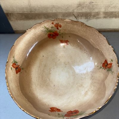 Sale Photo Thumbnail #384: Large antique ceramic or earthenware footed bowl featuring a scalloped rim and a shaded brown-to-tan glaze. Decorated with hand-painted or transfer floral poppy designs on one side and an interior, and a portrait of a monk drinking beer/ale on the opposit