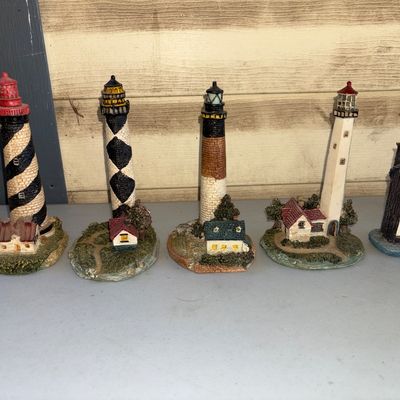 Sale Photo Thumbnail #145: A collection of 5 detailed nautical resin figurines featuring four various lighthouse designs (including Cape Hatteras, Diamond Shoals, and Bodie Island styles) and one seagull-topped wooden pilings figurine with a built-in thermometer. Items are in good 