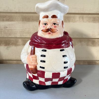 Sale Photo Thumbnail #58: 9in tall. 
Hand-painted ceramic cookie jar featuring an Italian chef in a white toque, red neck scarf, and checkered pants, holding a spoon or rolling pin. Shows minor surface wear, fine crazing in the glaze, and small paint scuffs consistent with age and