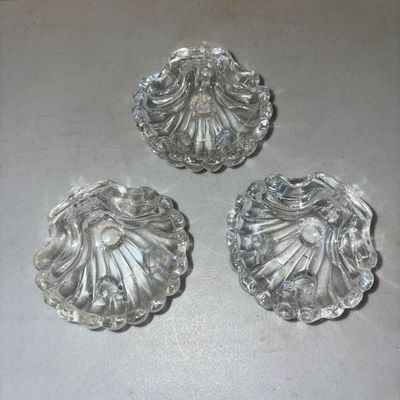 Sale Photo Thumbnail #213: A set of three matching vintage clear pressed glass open salt cellars or small trinket dishes. Designed in a scalloped sea shell shape with small ball feet underneath. Made of heavy pressed glass. All three pieces appear to be in good condition with no vi
