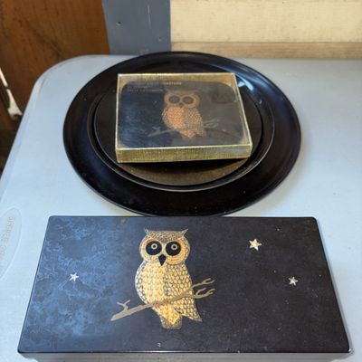 Sale Photo Thumbnail #34: Vintage Mid-Century Couroc of Monterey resin table accessory set featuring an owl design with inlaid brass/gold-tone stars and branch details. Includes a hinged rectangular box, a boxed set of six 'Conversation Coasters', and a round black serving tray. I